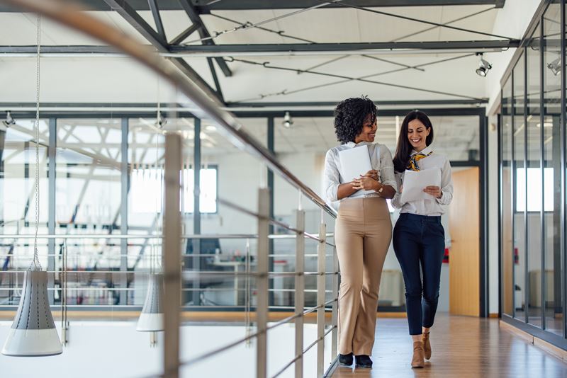 Two women walk and talk in the office